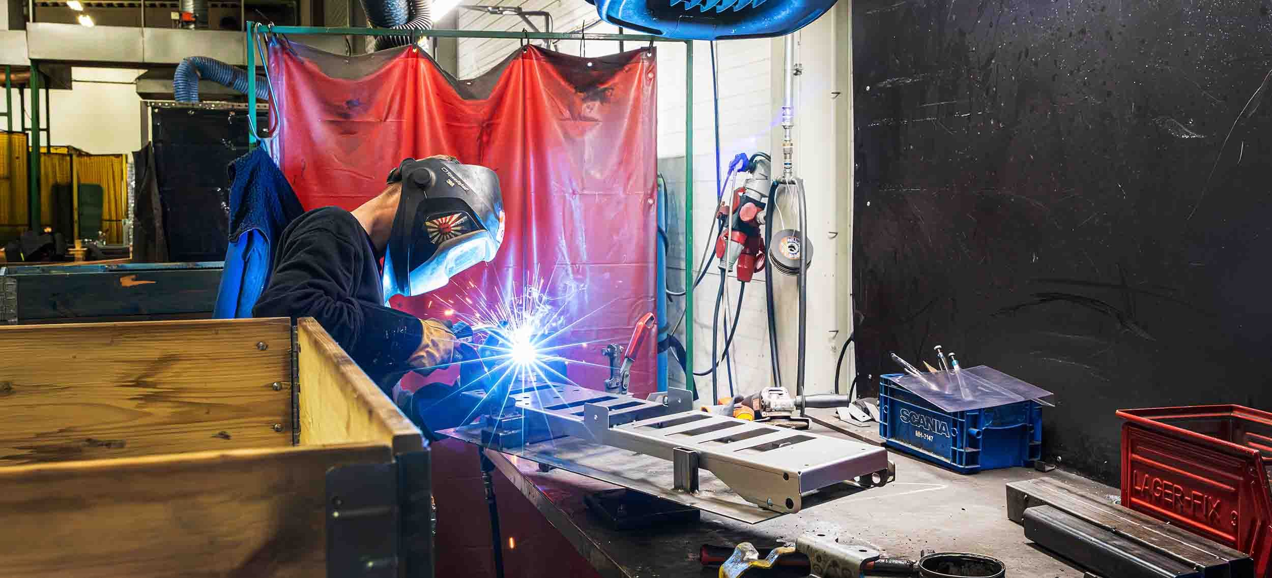 Man står och svetsar i produktion på lång avstånd. 